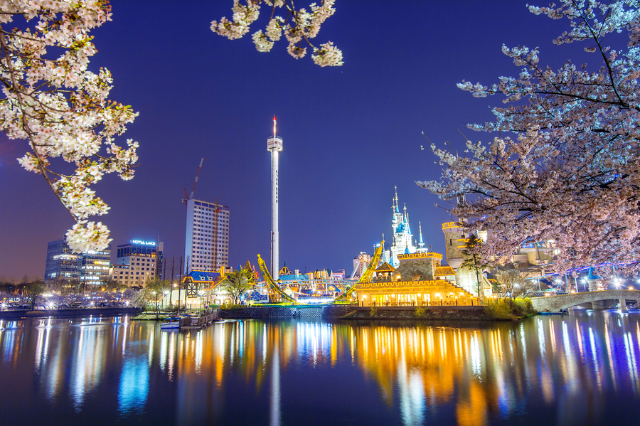 Vista nocturna de Lotte World en Seúl con cerezos en flor